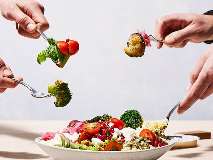 4 people with a fork digging into a salad bowl