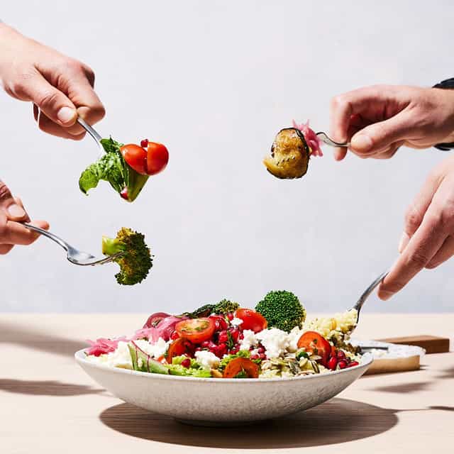 4 people with a fork digging into a salad bowl