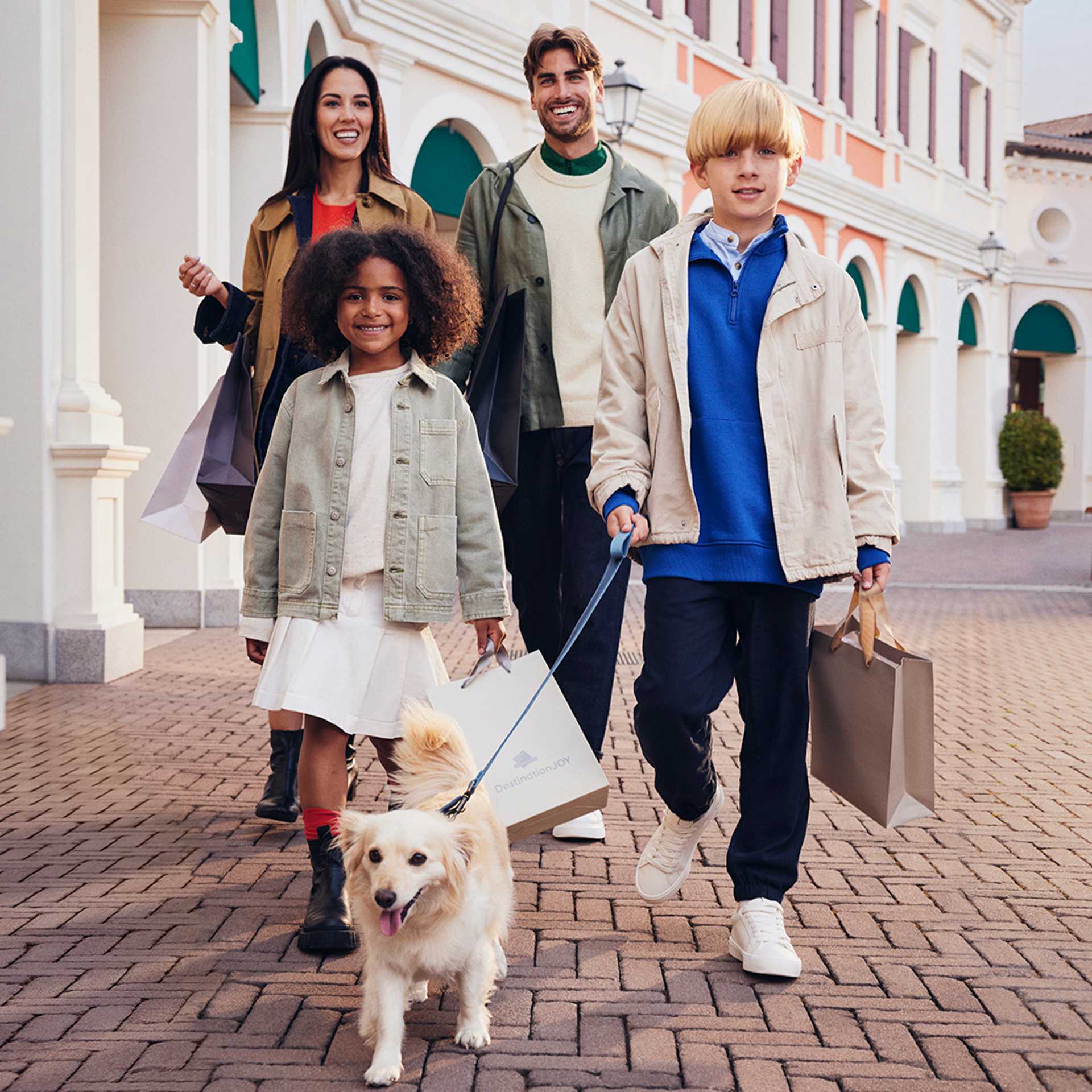 A happy family walking with shopping bags and their dog.