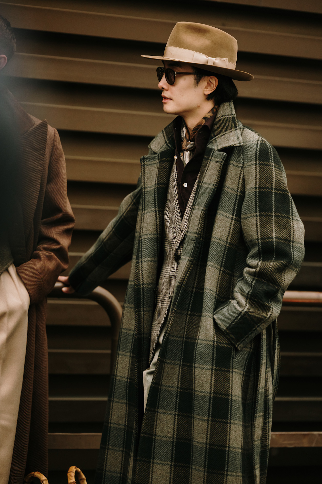 A man wearing a green and grey large check print double breasted jacket made of a thick wool material