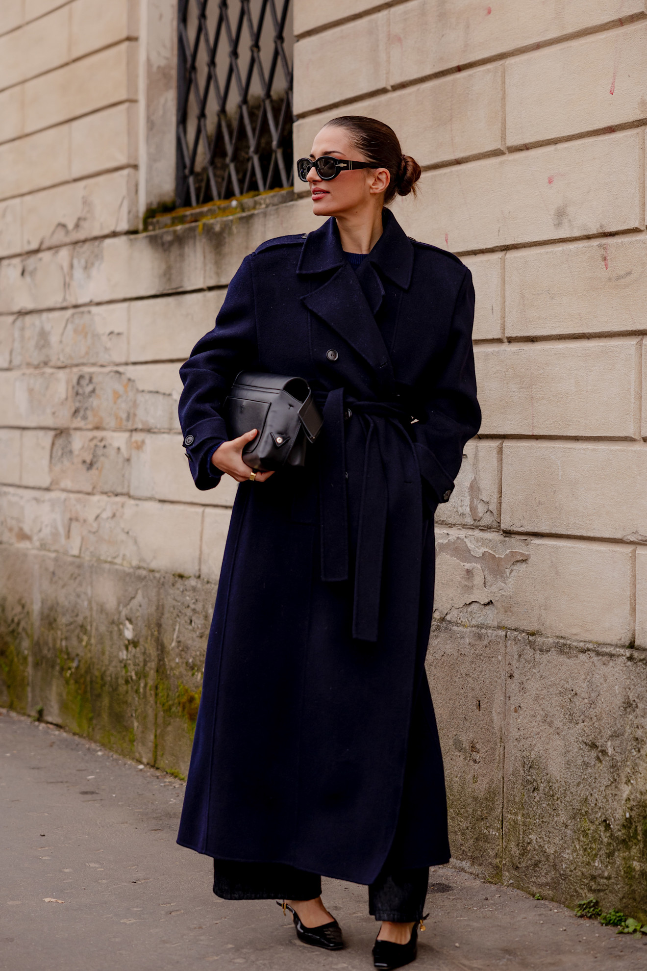 A woman wearing a classic wool trench coat in a dark midnight blue